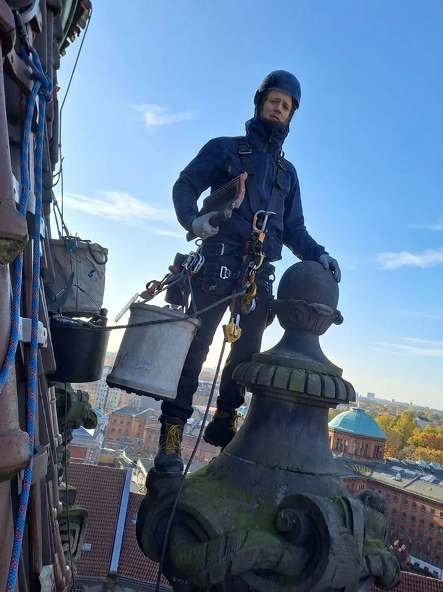 Antonio Braune, Industriekletterer, auf einem historischen Turm im Seilzugangsgeschirr